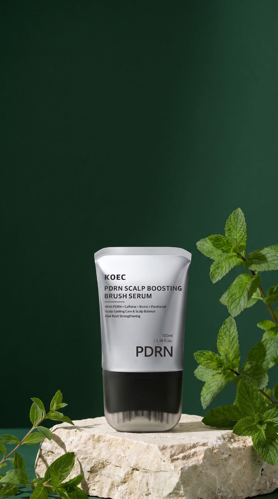 El tubo del sérum KOEC PDRN sobre una piedra, con fondo verde oscuro y hojas de menta