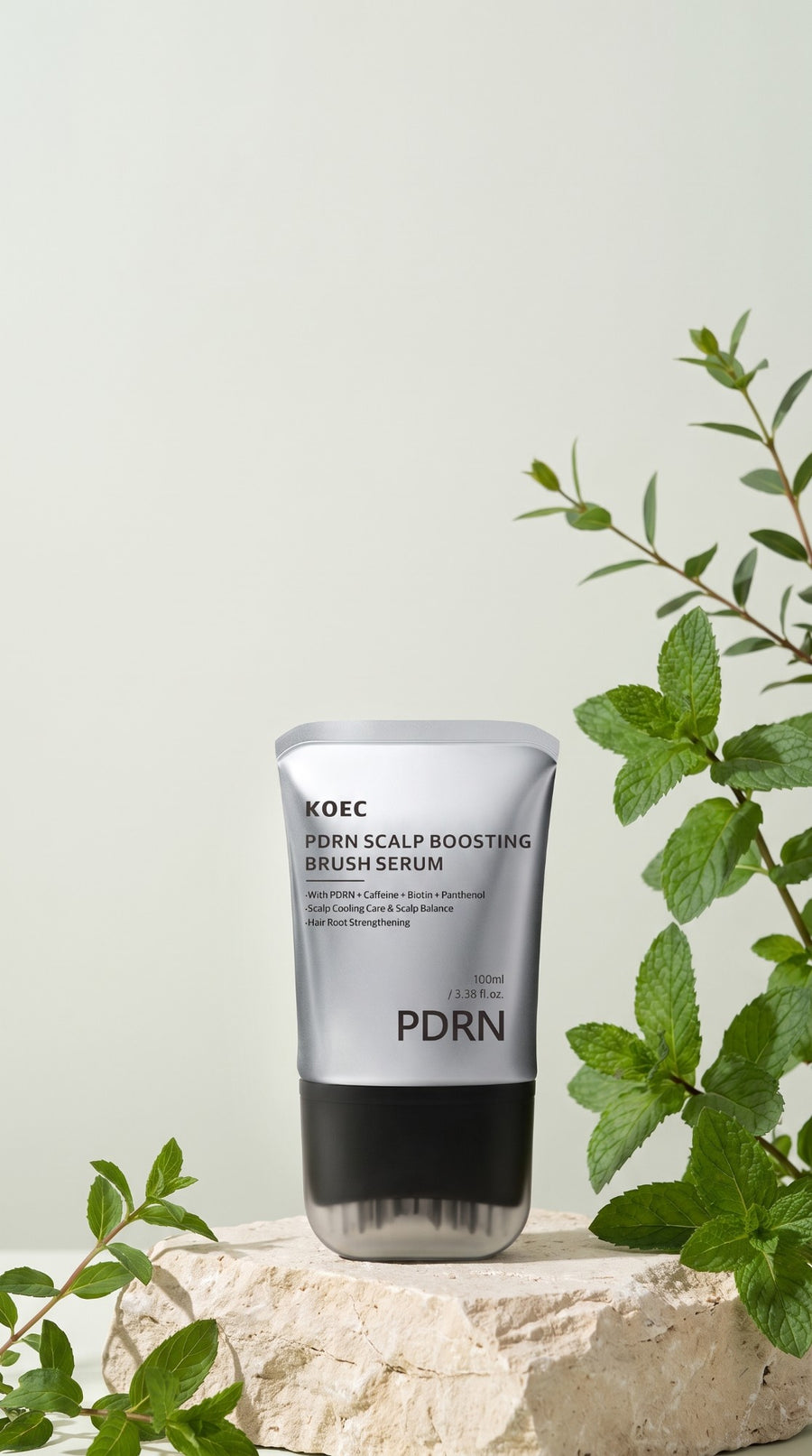 El tubo del sérum KOEC PDRN sobre una piedra, entre hojas de menta